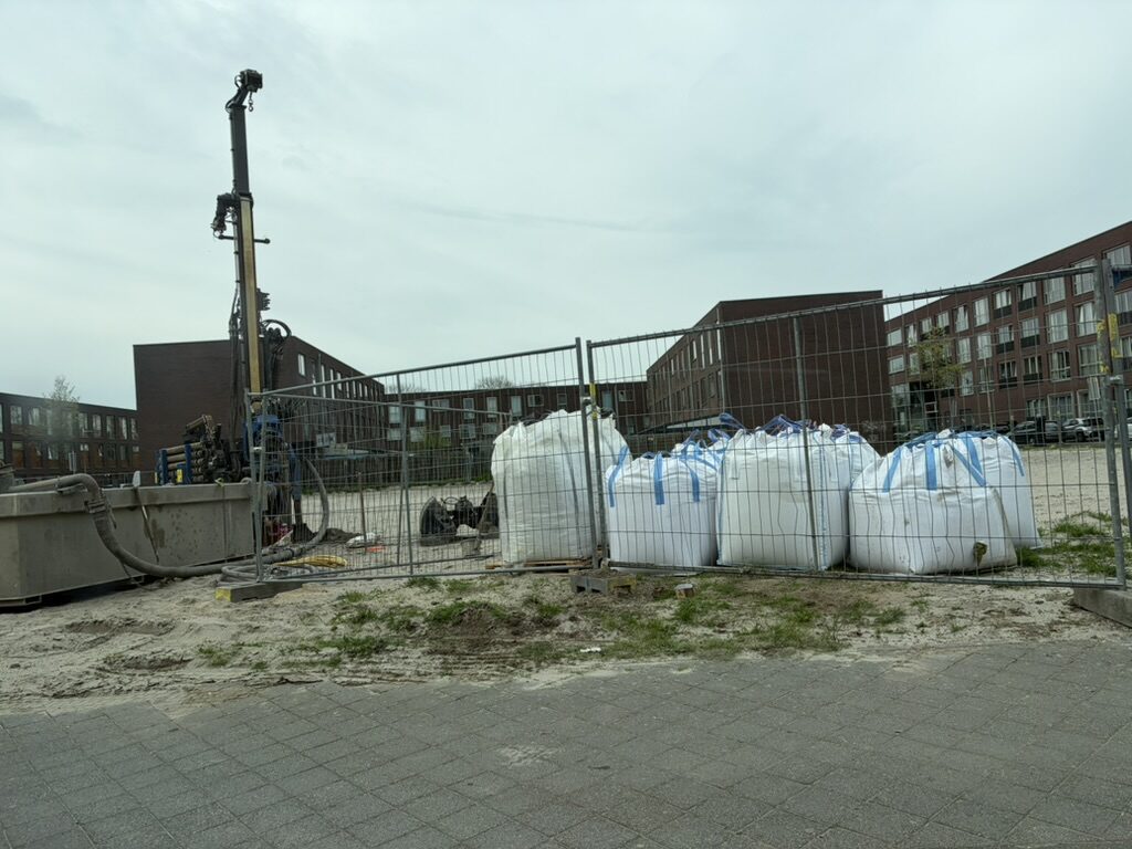 Drilling rig and bigbags behind the construction fence