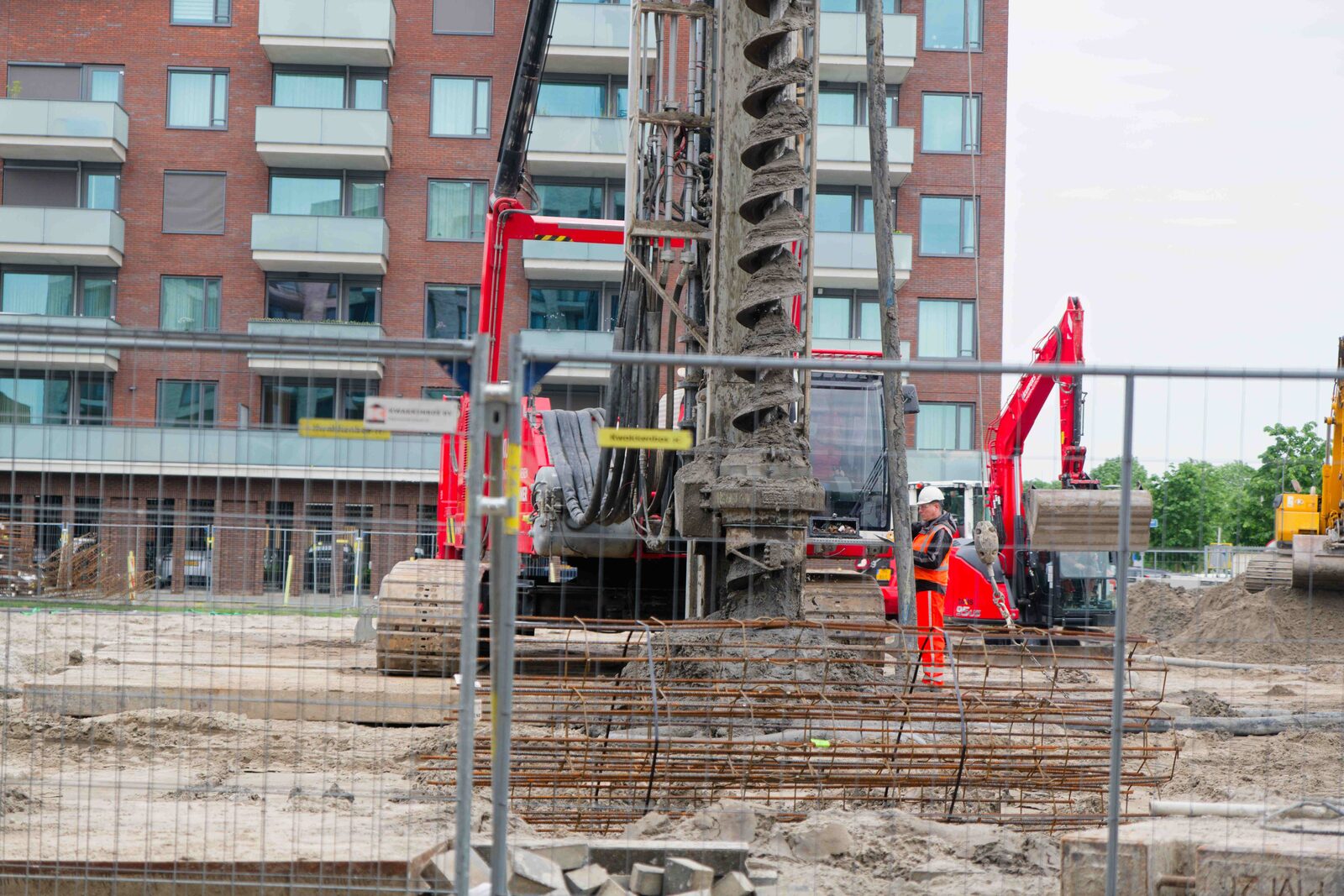 CFA drilling rig with auger raised, rebar cage in foreground